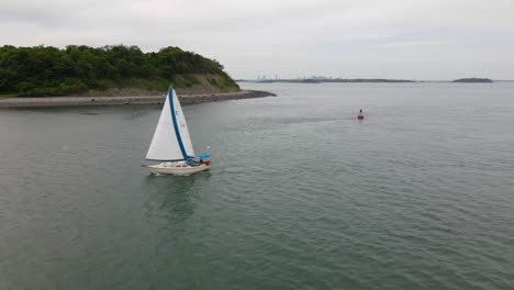 Paso-Bajo-Aéreo-De-Un-Pequeño-Velero,-Navegando-Cerca-De-La-Isla