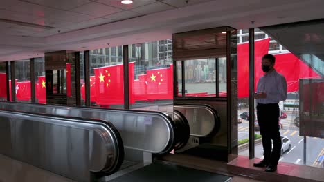 A-man-talks-on-the-phone-in-front-of-flags-of-the-People's-Republic-of-China-and-the-Hong-Kong-SAR-are-seen-in-a-street-during-Hong-Kong's-handover-to-China-anniversary