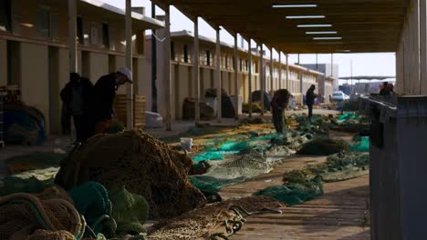 Several-port-workers-mending-and-fixing-fishing-nets-after-a-day's-work