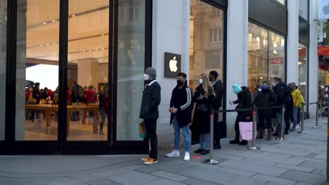 Personas-Con-Mascarillas-Haciendo-Fila-Frente-A-La-Tienda-De-Manzanas-En-Invierno