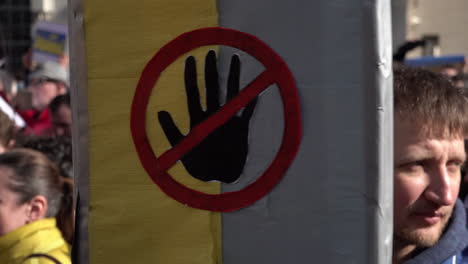 Während-Einer-Protestaktion-Gegen-Die-Russische-Invasion-In-Der-Ukraine-Wird-Ein-Plakat-Mit-Einem-Verbotsschild-Auf-Einer-Ukrainischen-Flagge-Hochgehalten