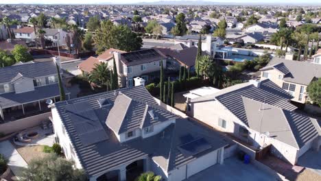 An-aerial-drone-shot-rising-up-from-a-house-to-reveal-a-beautiful-residential-suburb-in-Victorville,-in-the-distance-the-arid-landscape-and-scenic-mountains-of-the-Mojave-Desert,-California,-USA