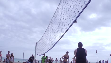 Team-Von-Volleyballspielern,-Die-Während-Eines-Beach-Volleyball-Wettbewerbs-Mit-Weitwinkel-In-Zeitlupe-Gefilmt-Werden-Und-Den-Ball-Weitergeben-Und-Einen-Punkt-Erzielen