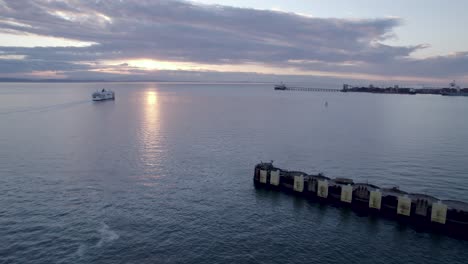 Aerial-forward-over-Tsawwassen-Vancouver-terminal-at-sunset-with-ferry-in-background,-British-Columbia-in-Canada