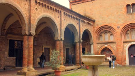 Toma-Panorámica-De-La-Basílica-De-Santo-Stefano-También-Llamada-Las-Siete-Iglesias-Y-El-Claustro-Con-Columnas-Y-Paredes-De-Ladrillo-En-Bolonia,-Italia,-Europa