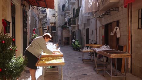 Mujer-Vendiendo-Productos-En-Una-Calle-Angosta-En-Bari,-Italia