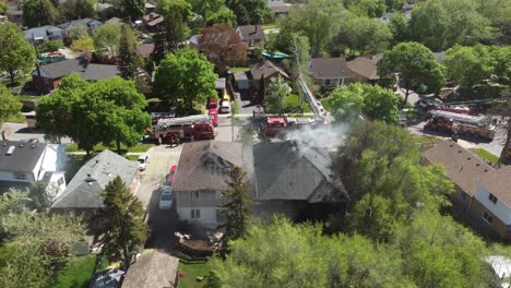 Vista-Aérea-De-Los-Camiones-De-Bomberos-Que-Tienden-A-Albergar-Incendios-En-Los-Suburbios-De-Toronto-Con-Humo-Saliendo-De-La-Azotea