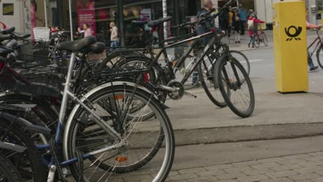 Portabicicletas-Abarrotado-Cerca-De-Gente-Caminando-En-Bicicleta-En-La-Calle-Balvarian-En-El-Centro-De-Tubingen,-Alemania,-Europa,-Toma-Panorámica