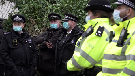 Eine-Gruppe-Von-Polizeibeamten-Aus-Großstädten,-Die-Schützende-Chirurgische-Gesichtsmasken-Tragen,-Schaut-Zu,-Wie-Sich-Während-Der-Covid-Pandemie-Ein-Protest-Versammelt