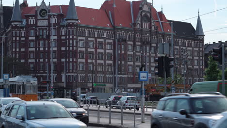 Traffic-moves-through-Nagyvarad-Square-in-Budapest,-past-Count-Haller-Street-building