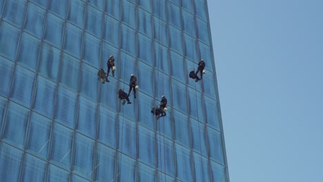 Primer-Plano-De-Limpiadores-De-Ventanas-Colgando-Y-Balanceándose-De-Un-Muro-Cortina-De-Vidrio-De-Un-Moderno-Rascacielos,-Santiago-De-Chile