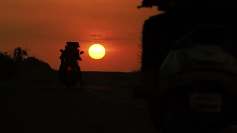 Vista-Trasera-Baja-De-La-Conducción-De-Motocicletas-En-La-Carretera-Durante-La-Puesta-De-Sol-En-La-India-En-La-Ciudad-De-Diu