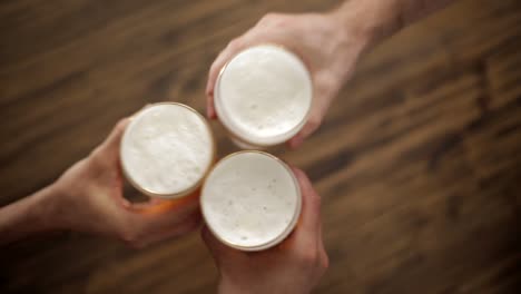 three-hands-with-a-glass-of-beer-toasting-together-to-celebrate-something