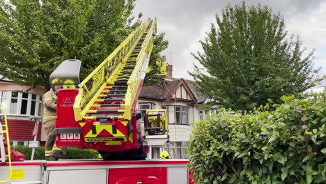 Un-Camión-De-Bomberos-Con-Escalera-Aérea-De-La-Brigada-De-Bomberos-De-Londres-Asiste-A-La-Escena-De-Una-Casa-En-Una-Calle-Residencial