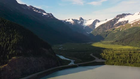 Aerial-view-over-natural-landscape-in-Alaska-wilderness-with-snow-on-mountain-peaks,-sunny-summer-day