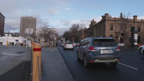 El-Tráfico-Conduce-Por-Davey-Street-En-Carretera-Mojada,-Rodeado-De-Arenisca-Y-Edificios-De-Oficinas-En-Hobart,-Tasmania,-Australia