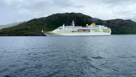 Toma-Media-Baja-Del-Crucero-Hamburg-Pasando-Por-El-Círculo-Polar-ártico-Frente-A-Verdes-Colinas-Rocosas-Y-Cielo-Nublado-En-Helgeland-Noruega