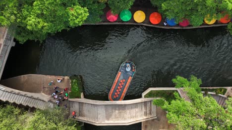 Small-boat-passes-under-bridge-beside-San-Antonio-River-Walk