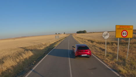 Aerial-follows-shiny-red-Mazda-car-driving-on-Spanish-country-road