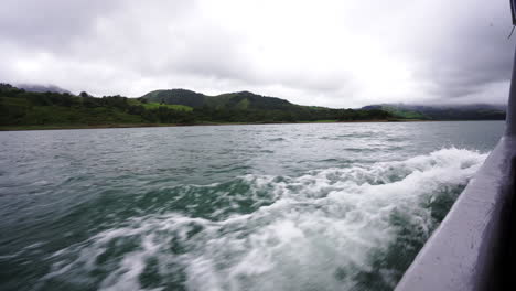 Costa-Rica-Central-America-Arenal-lagoon,-touristic-boat-crossing-the-lake-showing-natural-green-wilderness-landscape