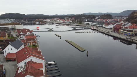 Antena-En-Movimiento-Hacia-Arriba-A-Lo-Largo-Del-Río-Marna-En-Mandal-Noruega---Revelando-El-Puente-Adolph-Tidemands-En-El-Fondo