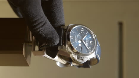 Vertical-De-La-Mano-De-Una-Persona-Con-Guantes-Negros,-Tome-Con-Cuidado-El-Reloj-Panerai-Swiss-Dentro-Del-Mostrador-De-Vidrio