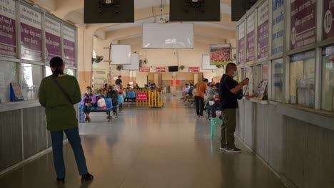 Passengers-at-busy-bus-station-terminal-buying-tickets-at-the-counter,-Thailand