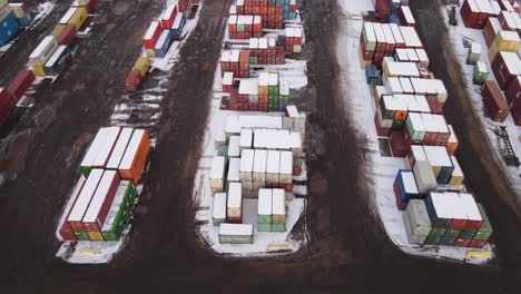 Toma-De-Envío-De-Contenedores-De-Envío-Cubiertos-De-Nieve-En-Un-Día-De-Invierno,-Apilados-Unos-Sobre-Otros,-Vista-Aérea