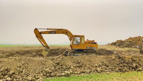 Una-Toma-Panorámica-De-Una-Excavadora-Destruyendo-Suelo-Fértil,-Un-Sorprendente-Contraste-Entre-La-Destrucción-De-La-Tierra-Y-La-Sequía-Que-Empeora-Debido-A-Ella