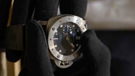 Vertical,-Closeup-Of-Panerai-Submersible-Men's-Watch-Held-By-Salesperson's-Hands-In-Black-Gloves-At-The-Boutique