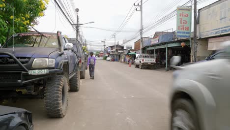 Nan-Province,-Thailand---November-22,-2022:-Shot-of-car-repair-shop-across-the-road-with-cars-passing-by-in-Nan-city,-Thailand-on-a-cloudy-day