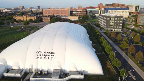 Aerial-sliding-shot-of-Lexus-Velodrome-during-golden-hour-next-to-a-nice-green-park