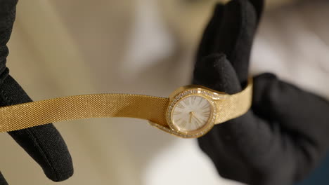 Vertikal-–-Hände-In-Schwarzen-Handschuhen-Halten-Eine-Piaget-Limelight-Gala-Uhr-Im-Roségoldgehäuse-Mit-Diamanten-Im-Brillantschliff-In-Einem-Juweliergeschäft