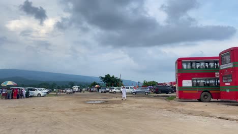 Experimente-El-Ajetreo-Y-El-Bullicio-De-Una-Terminal-De-Autobuses-En-La-Ladera-De-Bholaganj,-Sylhet,-Bangladesh,-Mientras-Los-Viajeros-Se-Embarcan-En-Sus-Viajes-En-Medio-De-Un-Telón-De-Fondo-De-Exuberantes-Colinas-Verdes