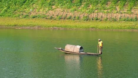 Ein-Asiatischer-Fischer-Steuert-Sein-Kleines-Boot-Bei-Sonnenuntergang-Auf-Dem-Fluss-Surma-Und-Fängt-Die-Ruhige-Schönheit-Des-Sanften-Lichts-Auf-Dem-Wasser-Ein