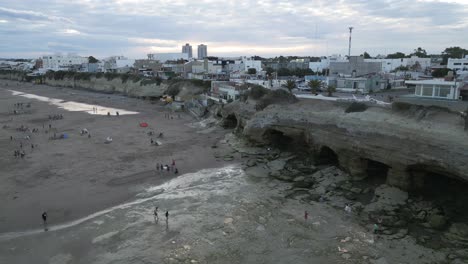 Luftdrohnen-Fliegen-über-Argentinische-Patagonische-Klippenstrandhöhlen,-Küstenstadt-Las-Grutas-In-Rio-Negro,-Menschen-Gehen-Auf-Weißem-Sand