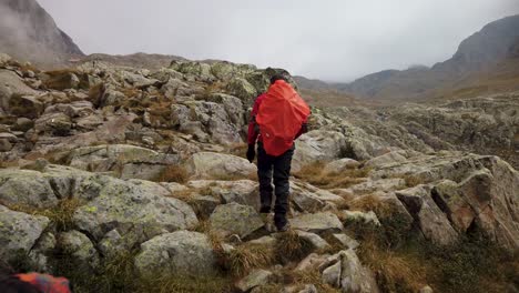 The-lider-of-a-group-of-hikers-stops-over-a-rocky-ground-and-points-to-something-at-the-left