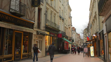 Tilt-down-shot-of-narrow-street-in-front-of-exterior-of-half-timbered-building-in-historic-town-of-Angers,-France-on-a-cloudy-day