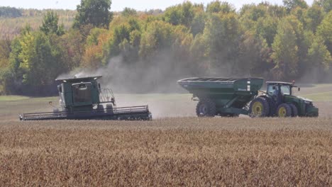 John-Deere-Kombiniert-Sojabohnen-An-Einem-Herbsttag-Mit-Einem-Traktor-Und-Einem-Getreidewagen-Im-Hintergrund