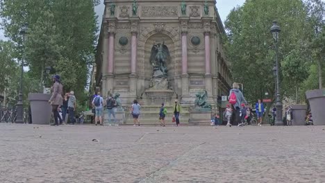 Una-Toma-En-Cámara-Lenta-De-La-Fontaine-Saint-michel-En-Las-Calles-De-París,-Con-Gente-Caminando