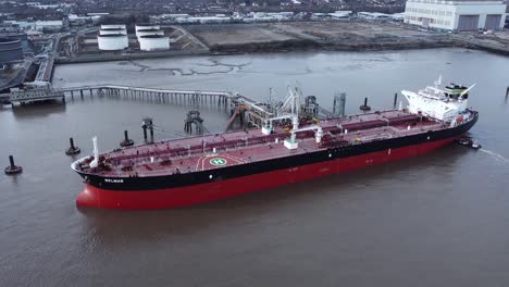 Aerial-rising-tilt-down-view-over-International-oil-tanker-docked-at-British-refinery-terminal