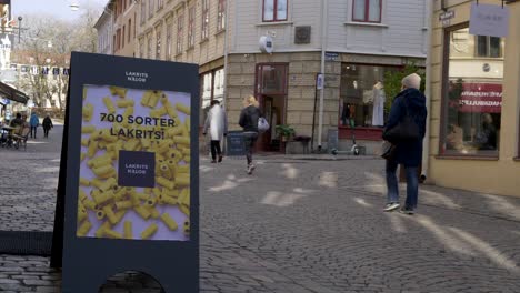 People-crossing-in-front-of-a-store-sign-in-Haga,-Gothenburg,-Sweden