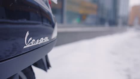 Primer-Plano-Del-Logotipo-De-Vespa-En-La-Parte-Trasera-Del-Vehículo-En-Un-Día-De-Invierno-Con-Nieve