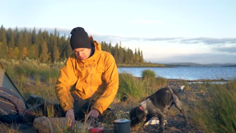 Einzelgänger-Camper-Mann-Und-Sein-Hund-Auf-Einem-Campingplatz-Am-Seeufer-Im-Wilden-Schweden-–-Weites-Zeitlupenfoto-Schieben