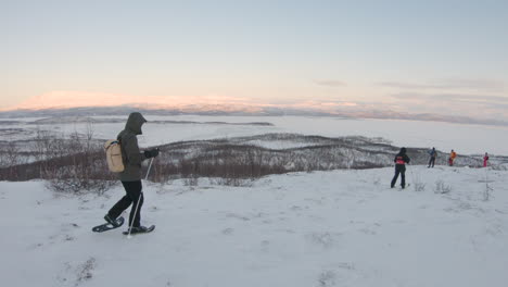 Wanderer-Mit-Schneeschuhen-Und-Stöcken,-Die-Bei-Sonnenaufgang-In-Der-Natur-In-Nordschweden-Auf-Einem-Berg-Wandern