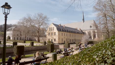 People-enjoying-on-benches-in-the-public-garden-of-La-Cambre-Abbey-in-Brussels,-Belgium