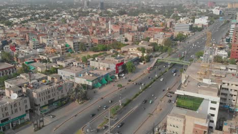 Vista-Aérea-De-La-Carretera-Con-Tráfico-Que-Pasa-En-La-Ciudad-De-Lahore-Y-Pájaros-Que-Pasan-Volando