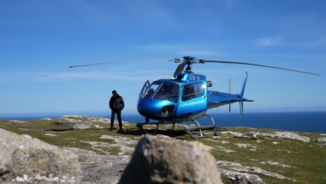 Privater-Tourhubschrauber-Auf-Dem-Gipfel-Der-Bergklippe-Mit-Blick-Auf-Die-Landschaft-Des-Blauen-Ozeans,-Der-Sich-Auf-Den-Start-Vorbereitet