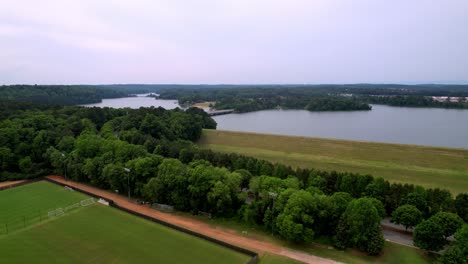 Campos-Atléticos-De-Clemson-En-Primer-Plano-Y-El-Lago-Hartwell-En-Segundo-Plano-Empuje-Aéreo