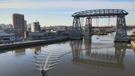 Static-aerial-of-boat-on-river-in-front-of-steel-bridges,-Buenos-Aires